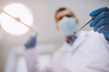 Erkek diş hekimi diş kliniğinde diş ayna tutan görünümünü kapat