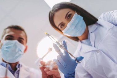 diş hekimi ve diş araçları ve şırınga modern diş kliniğinde tutan Erkek asistan