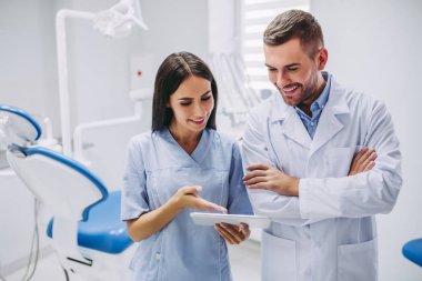 diş hekimi ve modern diş kliniği dijital tablet ekranında bakarak Yardımcısı