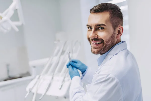 beyaz diş hekimi holding diş matkap gülümseyen ve diş kliniği kamerada bakarak portre