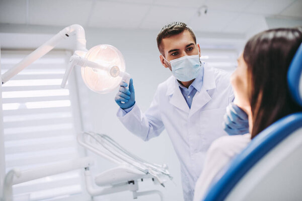 Male dentist checking female patient teeth in modern dental clinic
