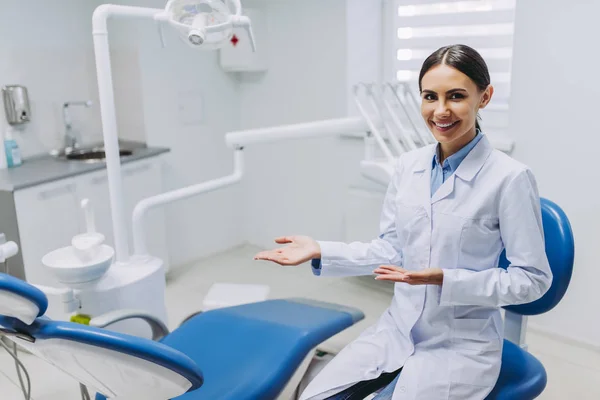Πορτρέτο Του Χαμογελαστό Γυναίκα Οδοντίατρος Που Δείχνει Θέση Της Εργασίας — Φωτογραφία Αρχείου