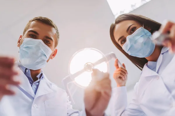 kadın diş hekimi ve diş araçları modern diş kliniğinde tutan Erkek asistan portre kadar kapatın