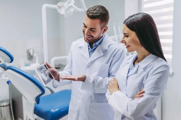 Doktor ve Yardımcısı x-ray modern diş kliniği ile dijital tablet ekranına bakarak portre