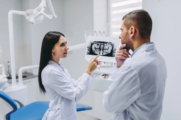 kadın Yardımcısı düşünceli erkek doktor röntgen modern kliniğinde, holding ile konuşurken portresi