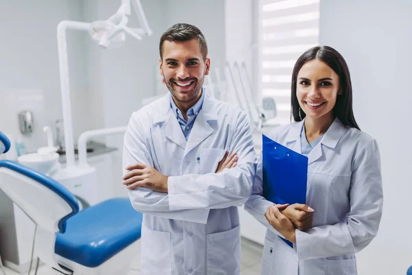 Kamera ayakta modern diş kliniği içinde işyerinde bakarak iki gülümseyen Doktor portresi