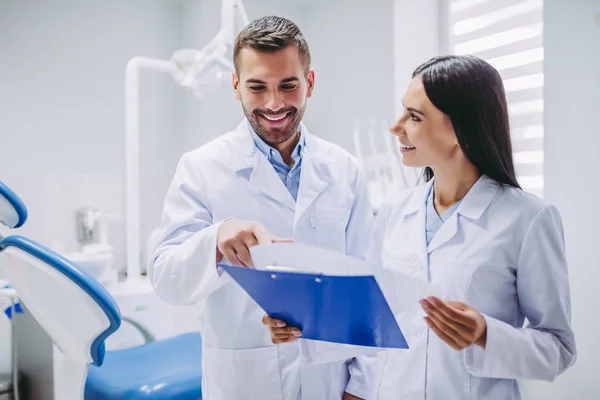 Lächelnde Zahnärzte Beim Blick Auf Das Klemmbrett Einer Modernen Zahnklinik — Stockfoto