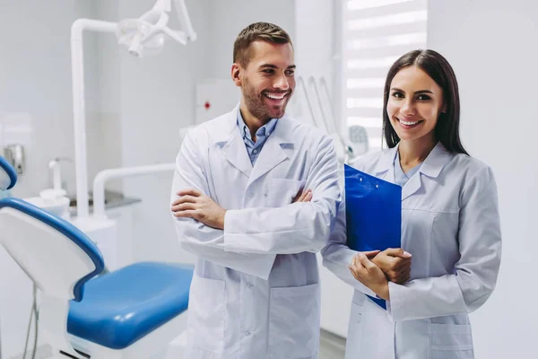Kamera ayakta modern diş kliniği içinde işyerinde bakarak diş hekimleri gülümseyen