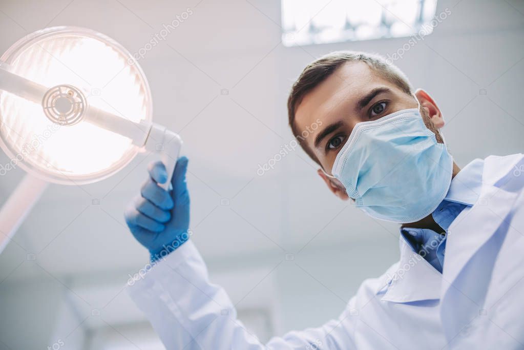 low angle view of doctor adjusting lamp in modern dental clinic