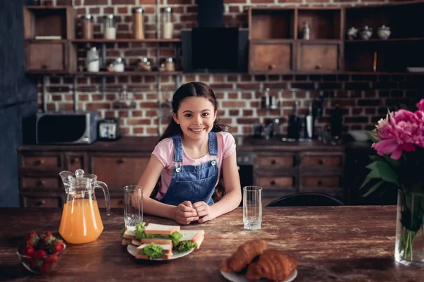 Retrato Chica Sonriente Mirando Cámara Mientras Está Sentado Mesa Cocina — Foto de Stock