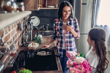 bir buket çiçek ve hediye kutusu o mutfakta ocakta yemek sırasında annesiyle tebrik kızı
