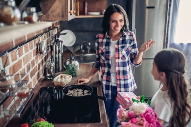 küçük kızı bir buket çiçek ve hediye kutusu o mutfakta ocakta yemek sırasında annesiyle tebrik