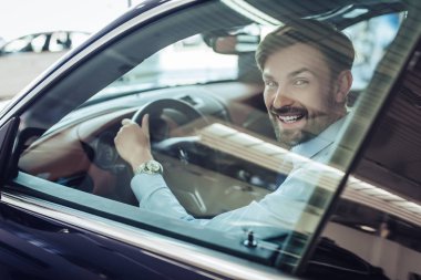 Arabada oturan ve kameraya bakarak beyaz işadamı yan görünüm