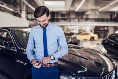 gülümseyen satıcı Bayilik salonda smartphone kullanarak portresi