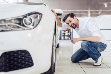 Yeni araba bayilik salonda bakarak gülümseyen beyaz adam portresi