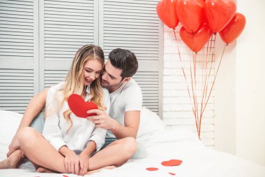handsome man with girlfriend reading gift card in the heart shape at valentines day