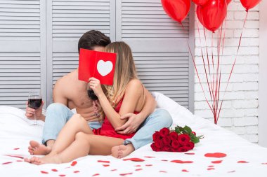 kız ve erkek arkadaşı hediye öpüşürken yatakta St Sevgililer günü kartı