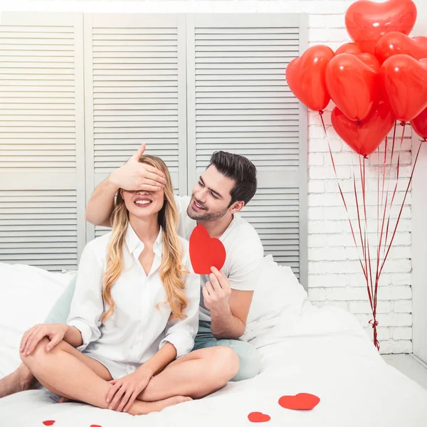 handsome man closing eyes his girlfriend for surprise, valentines day concept