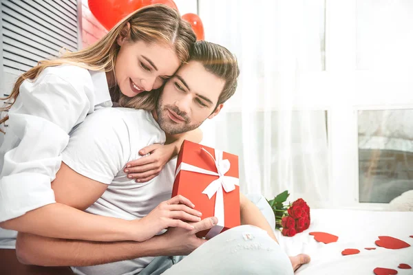 Retrato Mulher Abraçando Seu Namorado Segurando Caixa Presente Vermelho Sentado — Fotografia de Stock