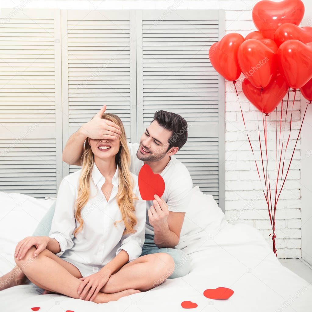 handsome man closing eyes his girlfriend for surprise, valentines day concept