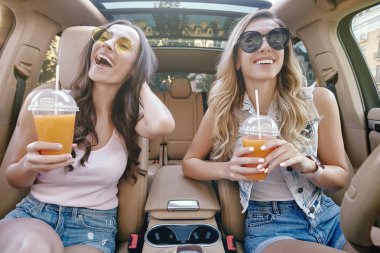 iki çekici kadın arabada otururken payet ile taze meyve suyu içme