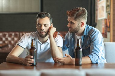onun arkadaşı bira içip birlikte konuşurken üzgün adam
