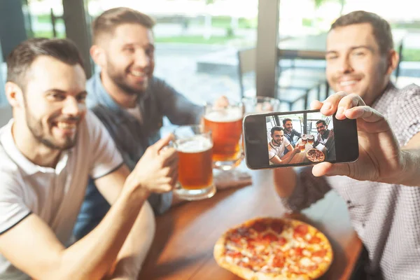 friends drinking beer, eating pizza and taking selfie on smartphone