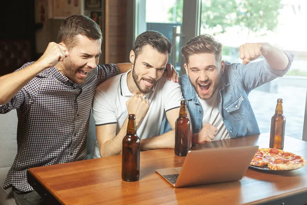 fans watching sports game on laptop in the cafe and drinking beer