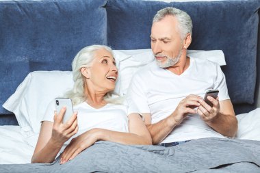 üst düzey çift yatakta akıllı telefonlar kullanarak portresi