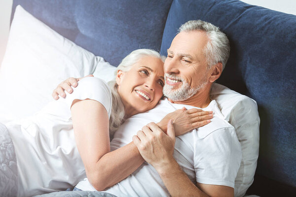 smiling woman hugging her husband in the bed