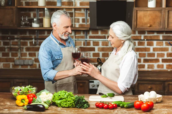 man giving glass of red wine to woman at the kitchen