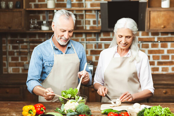 portrait of happy couple preparing salad at the kitchen together