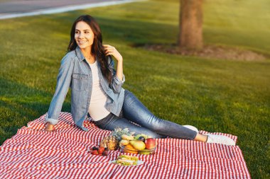 meyve ile küçük piknik üzerinde park, battaniyeye oturmuş kadın