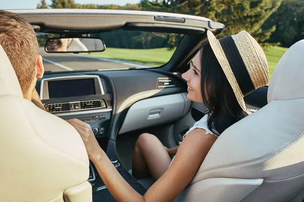 back view of young woman talking with boyfriend driving cabriolet