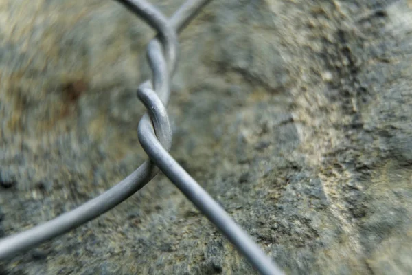 Aluminum wire twisted on stone object, macro background