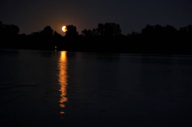 Gün batımından sonra alacakaranlık sırasında koyu mavi gökyüzünde güzel parlak kırmızı-turuncu ay yumuşak odak.