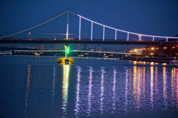 Мигающие огни на ночном мосту, сверкающие в отражении воды — стоковое фото