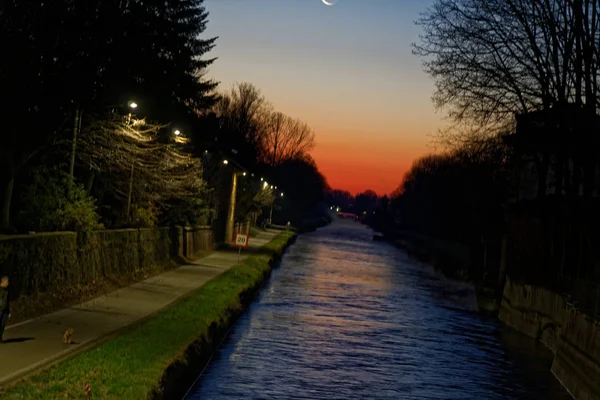 運河とカラフルな日没風景、運河の水の反射と深い赤とオレンジ色の空. — ストック写真