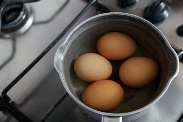 Варёные яйца в ковше с водой на кухне — стоковое фото