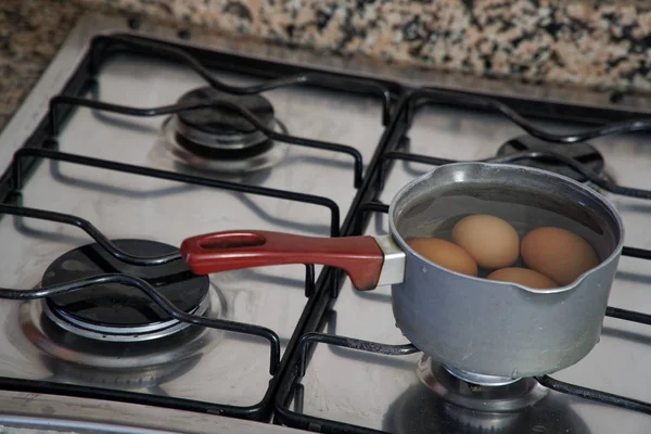 Варёные яйца в ковше с водой на кухне — стоковое фото