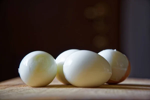 Жесткие яйца с оболочкой рядом на деревянной доске — стоковое фото