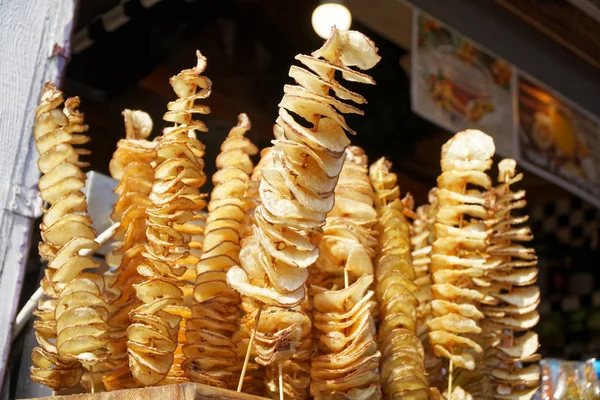 Çubuk üzerinde kızarmış patates cips, sarmal patates, ahşap çubukları, sarmal kızarmış. Pazarda yiyecek satmak. Sağlıksız kızarmış sokak yemekleri.