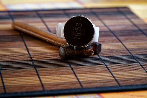 Reloj deportivo en color blanco sobre mesa de madera, reloj inteligente para correr y entrenar fitness. Martillo con mango de madera sobre fondo —  Fotos de Stock