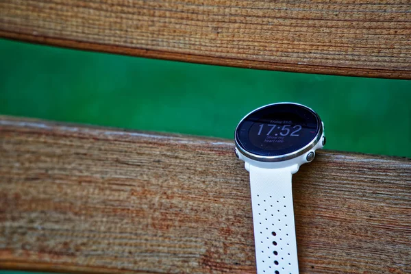 Sport watch for running white color on wooden bench. Fitness watch for tracking daily activity and power training.