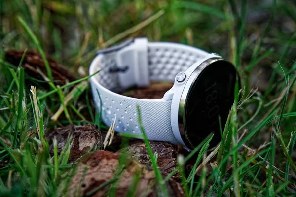Sportklocka för att köra vit färg på marken i gräset. Fitness Watch för att spåra daglig aktivitet och styrketräning. — Stockfoto