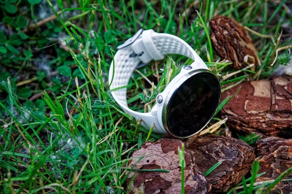 Sport watch for running white color on the ground in the grass. Fitness watch for tracking daily activity and strength training.
