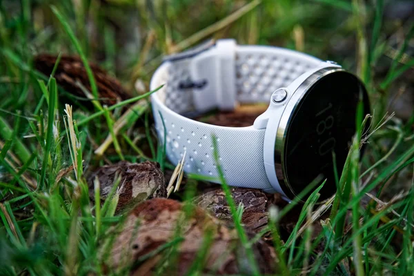 Sport watch for running white color on the ground in the grass. Fitness watch for tracking daily activity and strength training.