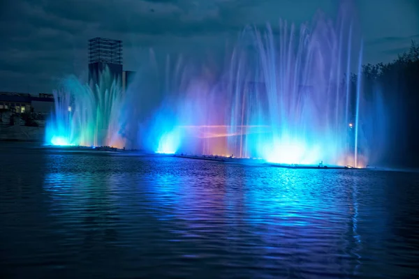Fontes de água coloridas com laser e reflexão de luz sobre o lago — Fotografia de Stock
