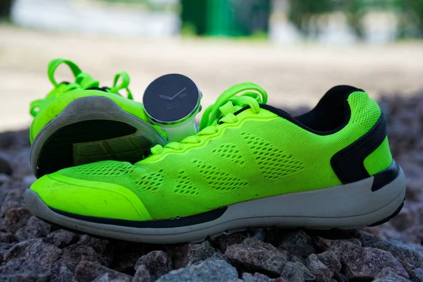 绿色跑鞋上交叉健身和铁人三项的运动手表。智能手表，用于跟踪日常活动和力量训练. — 图库照片