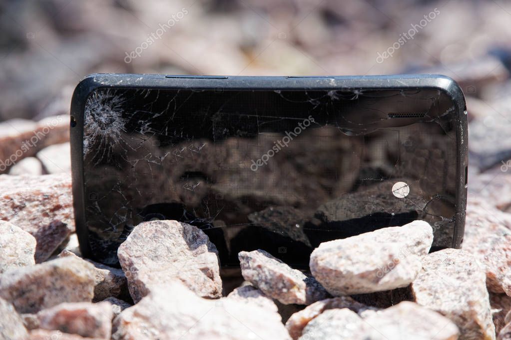 Broken glass of smartphone on gravel granite stones. Selective focus